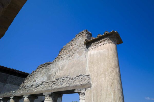 Colonna decorata alle Terme Stabiane di Pompei con dettagli architettonici e cielo blu.