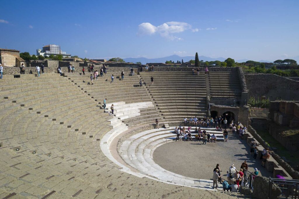 Anfiteatro romano di Pompei con turisti esplorando le rovine.