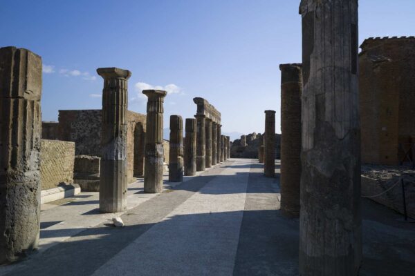 Resti di colonne romane nel foro di Pompei, illuminate dalla luce del sole.