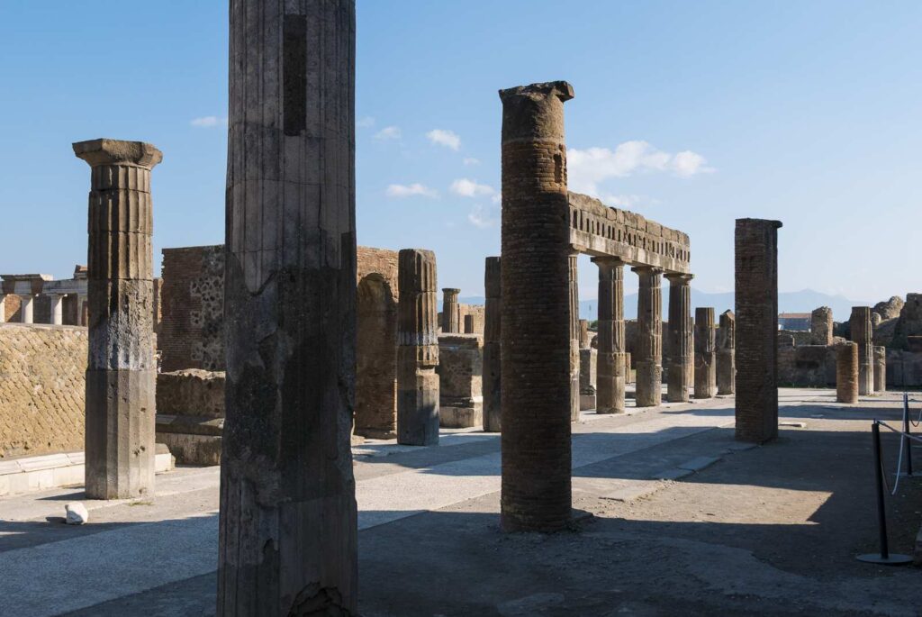 Rovine nel foro di Pompei con colonne antiche sotto un cielo sereno.